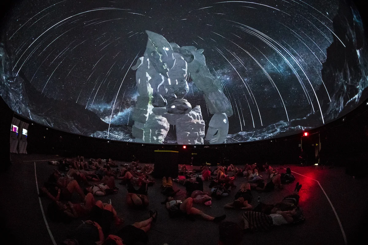 A seated audience beneath the projected dome