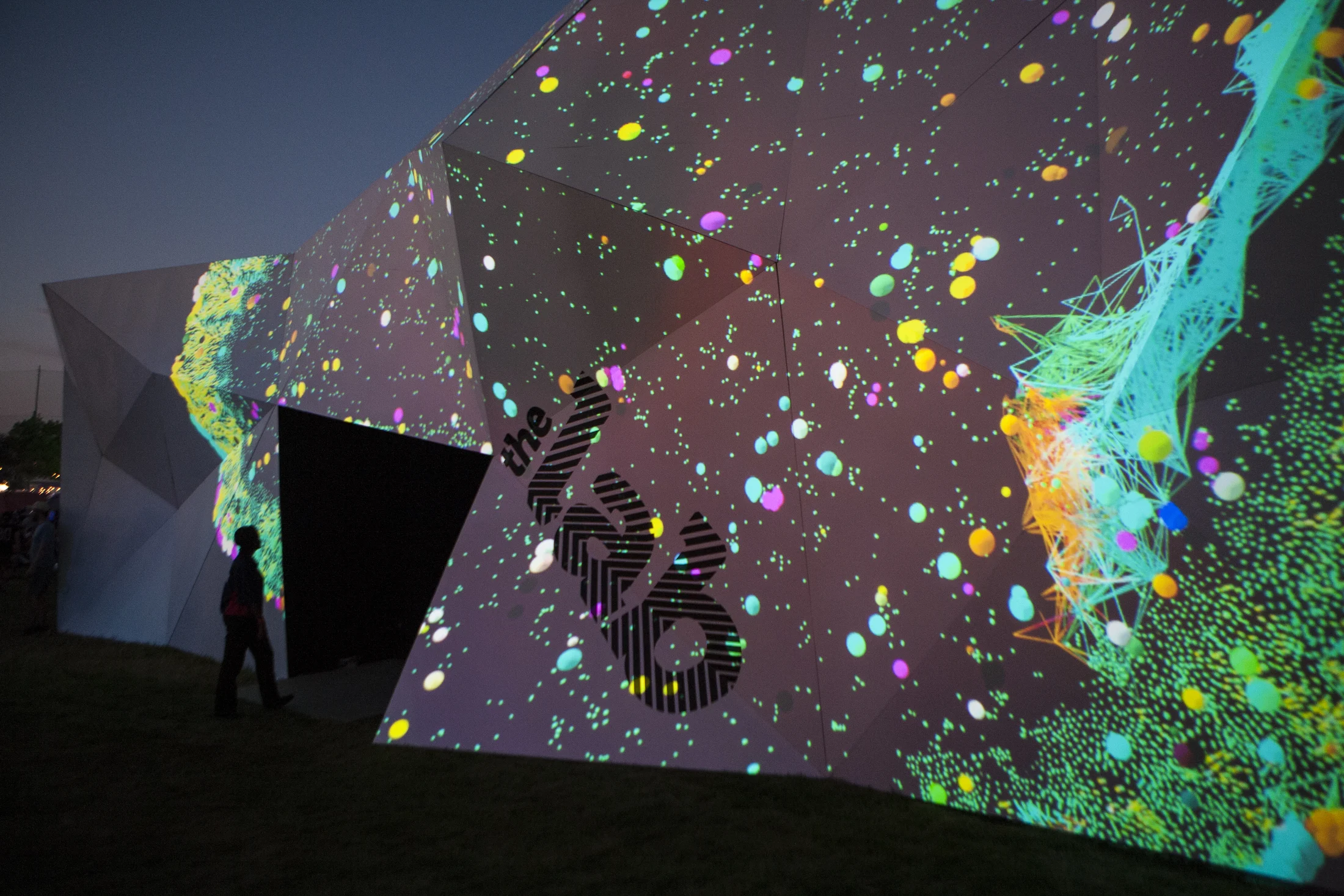 Visitors silhouetted against colorful projected shapes