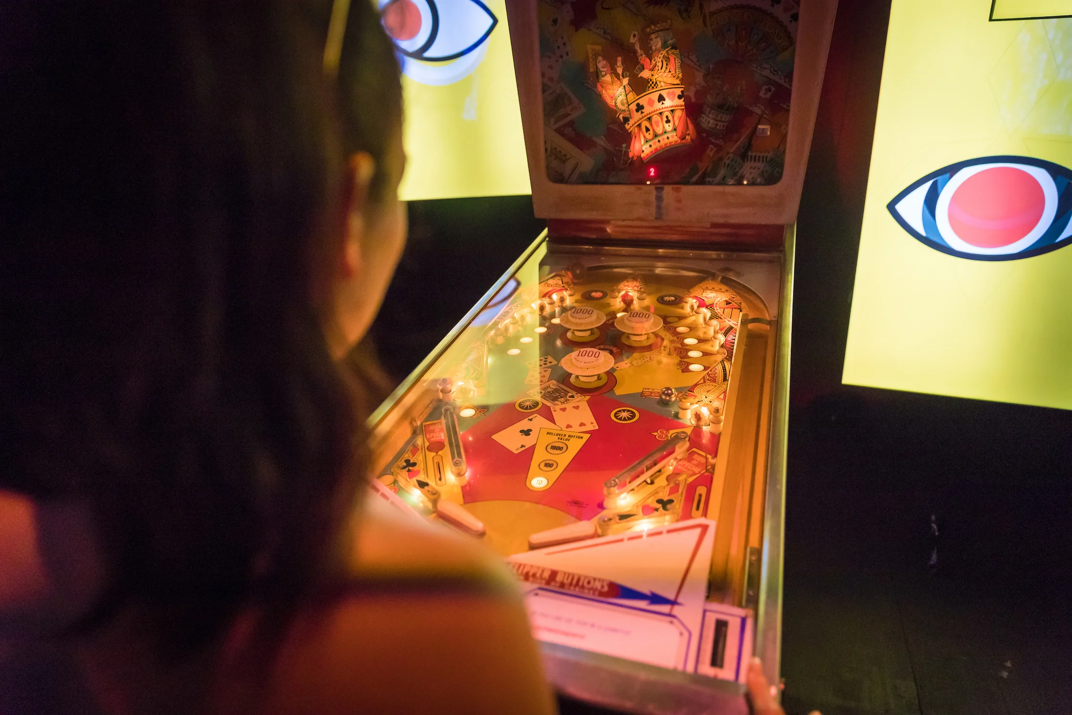 A visitor playing an illuminated pinball installation