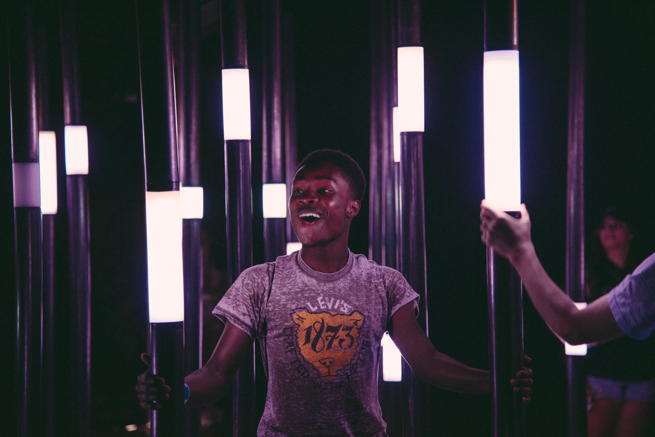 A visitor interacting with suspended glowing bars