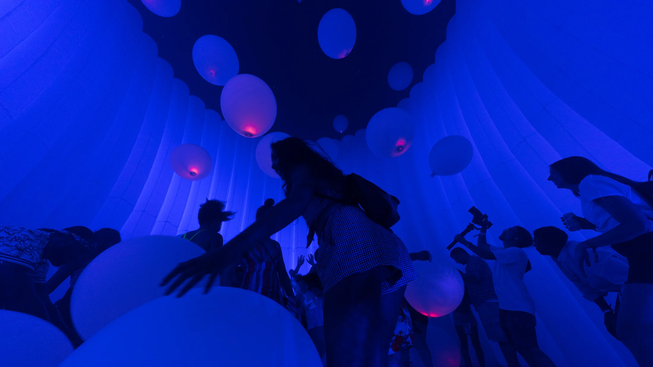 Visitors inside an environment of suspended glowing spheres