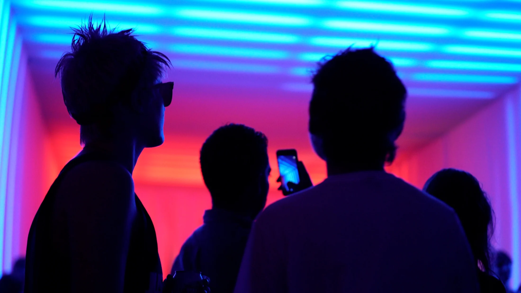 Visitors silhouetted against vivid red and blue light
